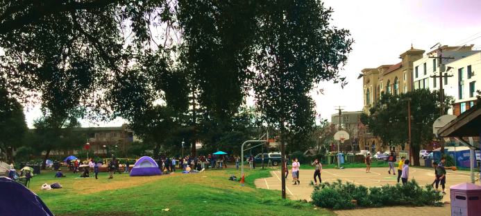 Panorama showing trees, basketball court, tents, and food distribution